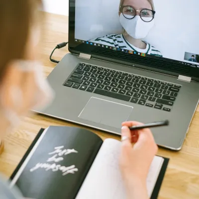 Person vor Laptop mit Notizblock während Coronazeit