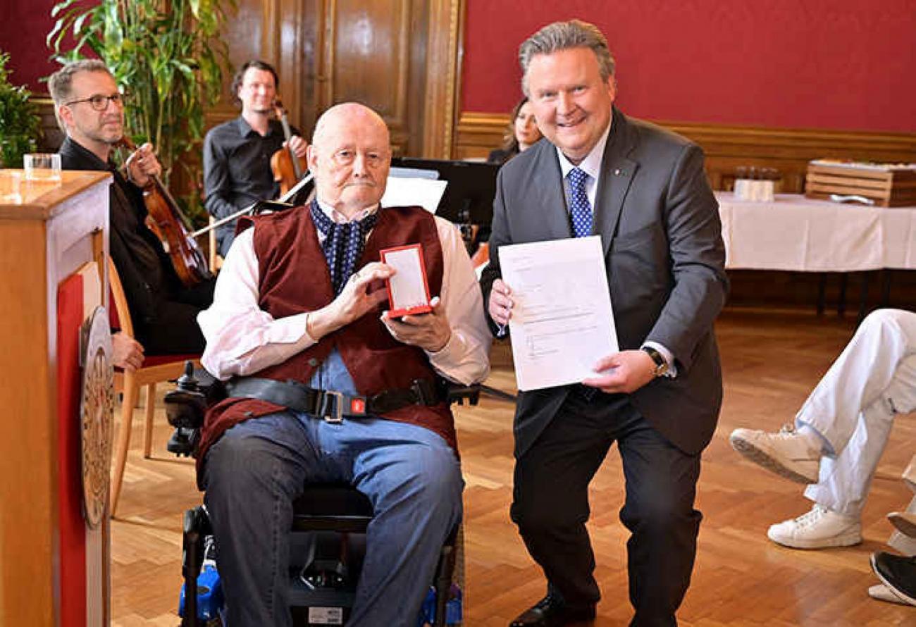 Bbr Alexander II im Rollstuhl erhält von Bgm. Ludwig eine Auszeichnung und Ehrenurkunde